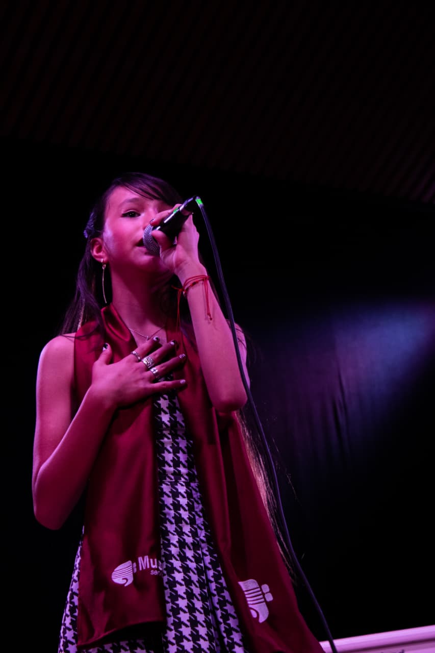 Estudiante cantando bajo las luces del escenario